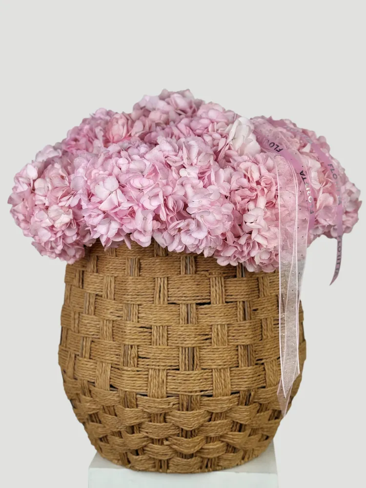 Full pink hydrangea dome in natural seagrass basket with Floritta branding
