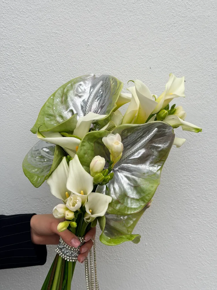 Elegant cream calla lilies and freesias with metallic anthurium leaves — Floritta
