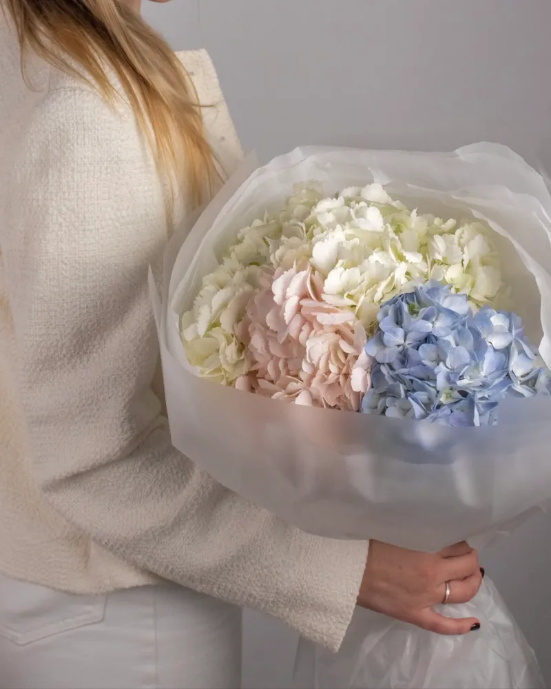 Elegant pastel peony, hydrangea and lisianthus wrapped bouquet held by woman — Floritta