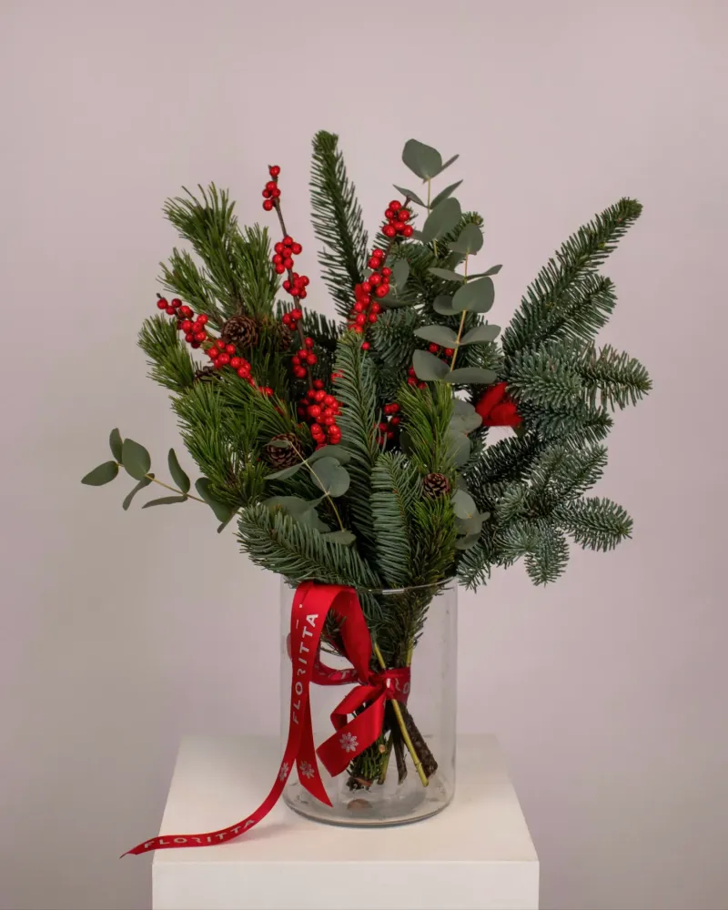 Christmas arrangement of red skimmia berries, evergreens and eucalyptus in glass vase — Floritta