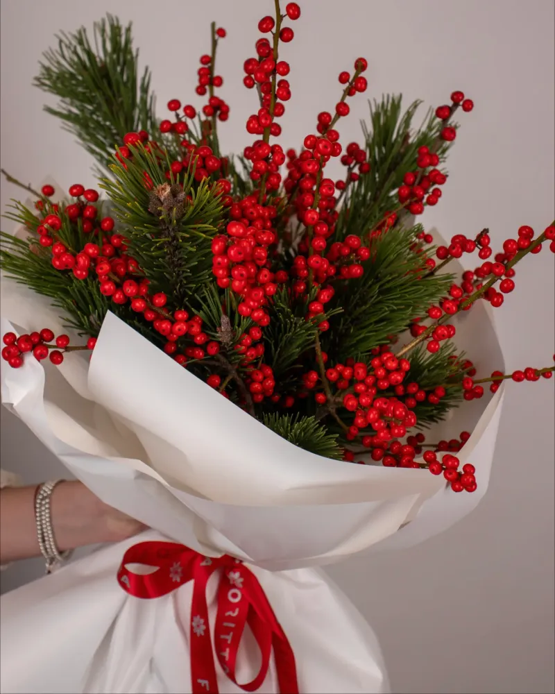 Abundant red skimmia berries and pine wrapped in white kraft paper — Floritta