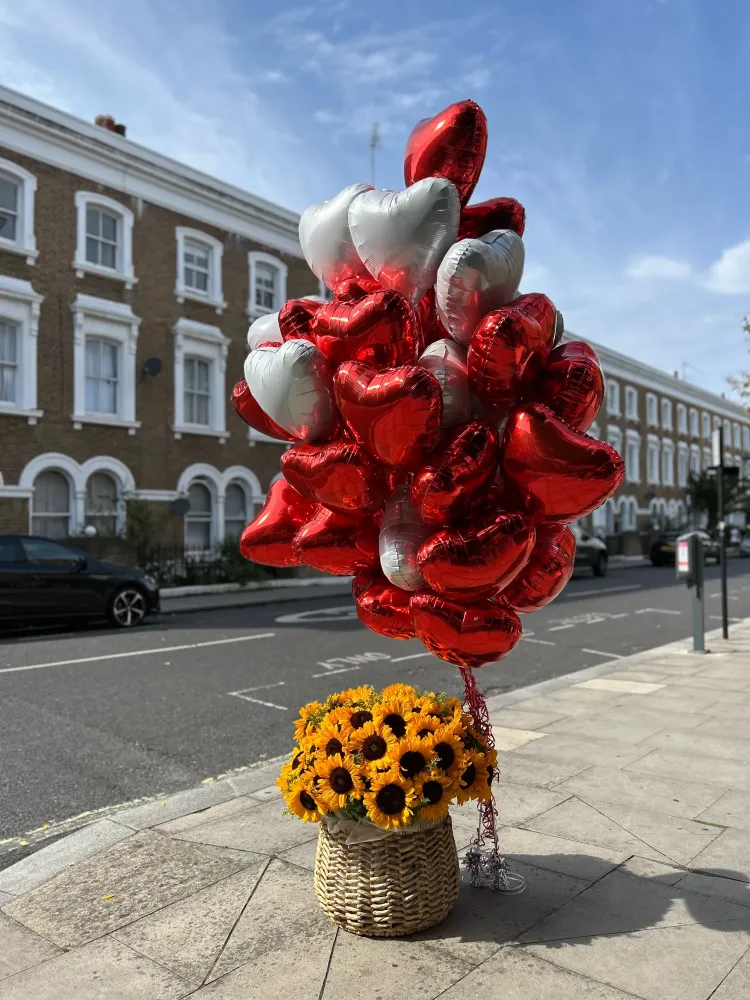 Sunflowers in woven basket with red and white heart balloons — Floritta
