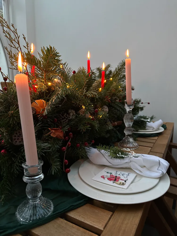 Full Christmas table arrangement with lit candles, festive greenery and berry sprigs — Floritta