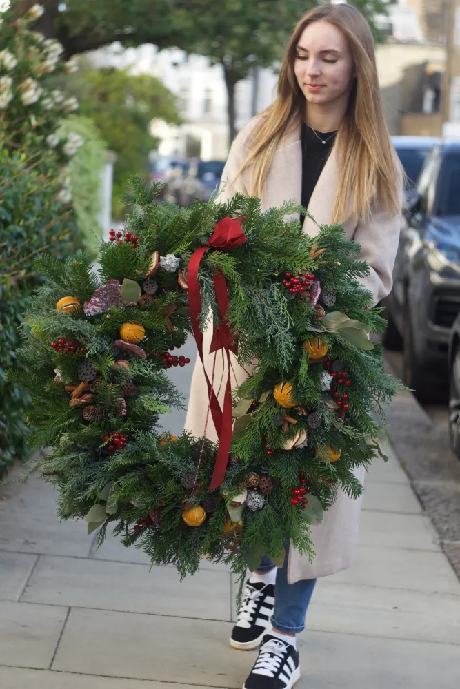 Christmas wreath featuring orange slices, roses and red ribbon bow — Floritta