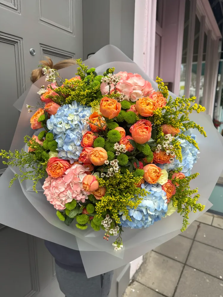 Coral garden roses and blue hydrangeas bouquet with white wrap — Floritta