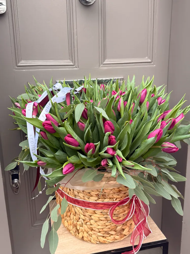 Abundant hot pink tulips and eucalyptus in straw basket — Floritta