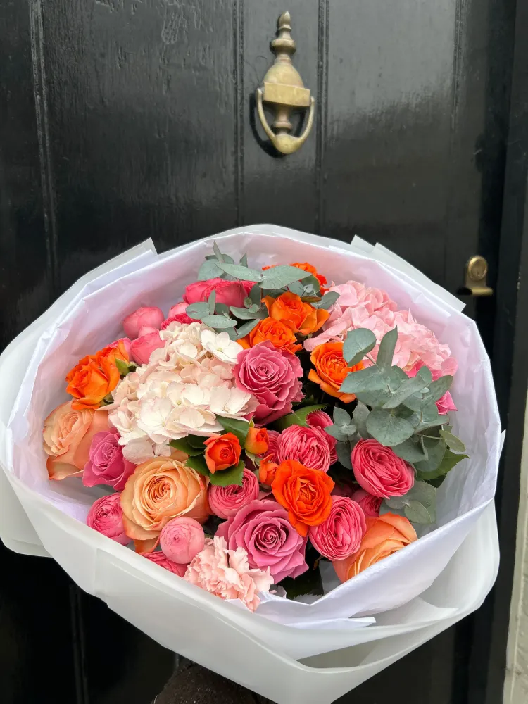 Vibrant hand-tied bouquet with roses, carnations and hydrangeas in warm tones — Floritta