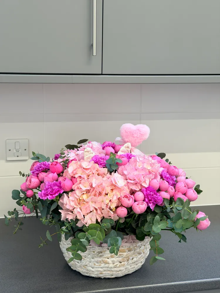 Abundant pink peony and rose arrangement with eucalyptus in woven basket — Floritta