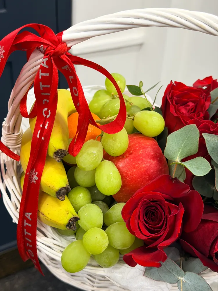 Red roses with green grapes, yellow pears and eucalyptus in white wicker basket — Floritta