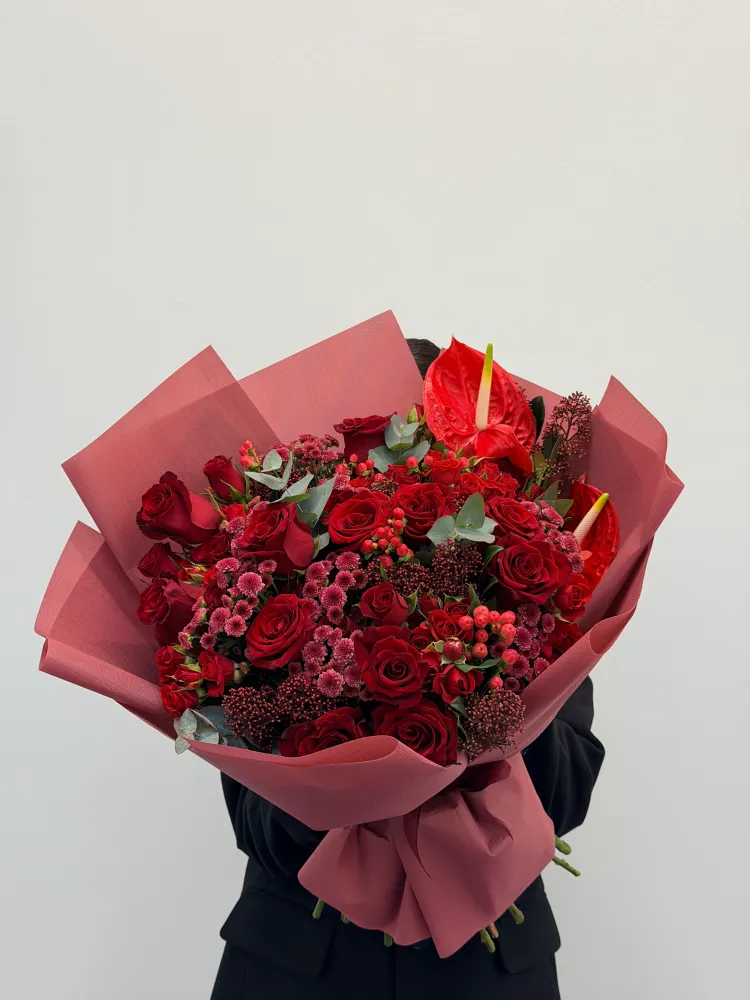 Luxury bouquet of red roses, anthurium and skimmia in pink wrap — Floritta