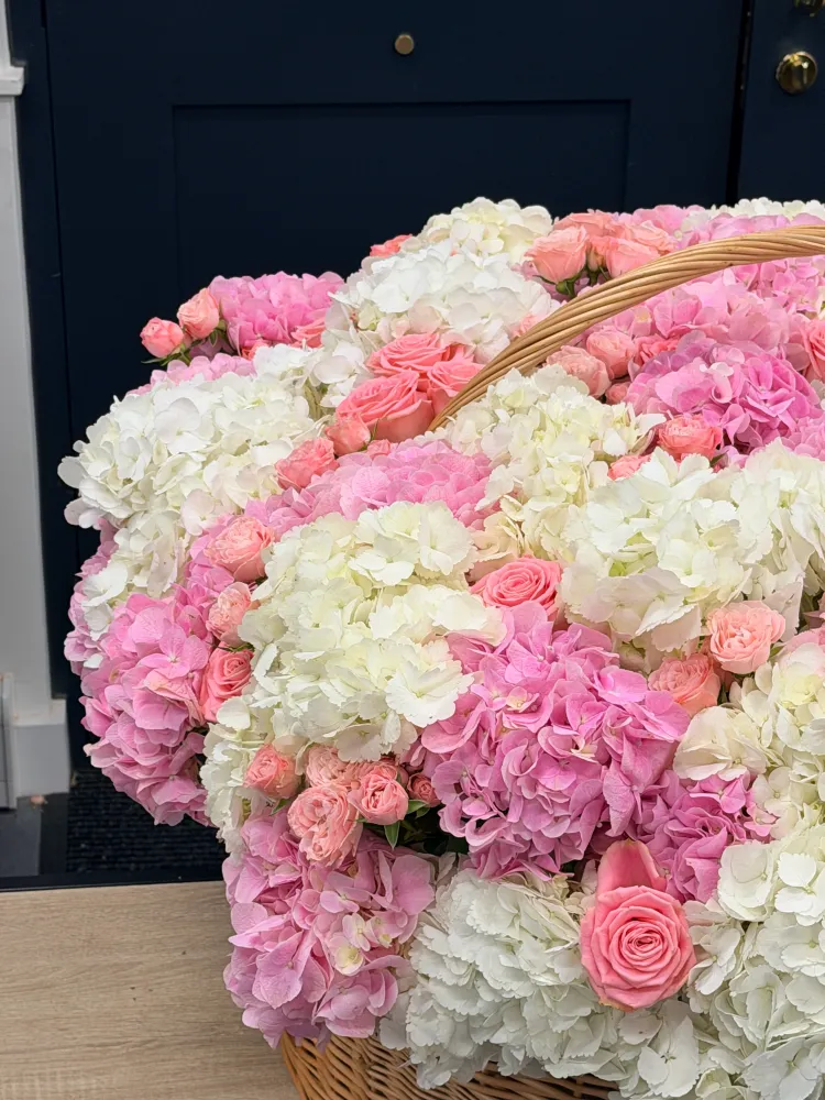 Abundant white, pink and coral hydrangea arrangement with spray roses in wicker basket — Floritta