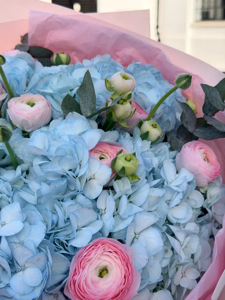 Close-up of blue hydrangea and blush ranunculus with eucalyptus greenery — Floritta