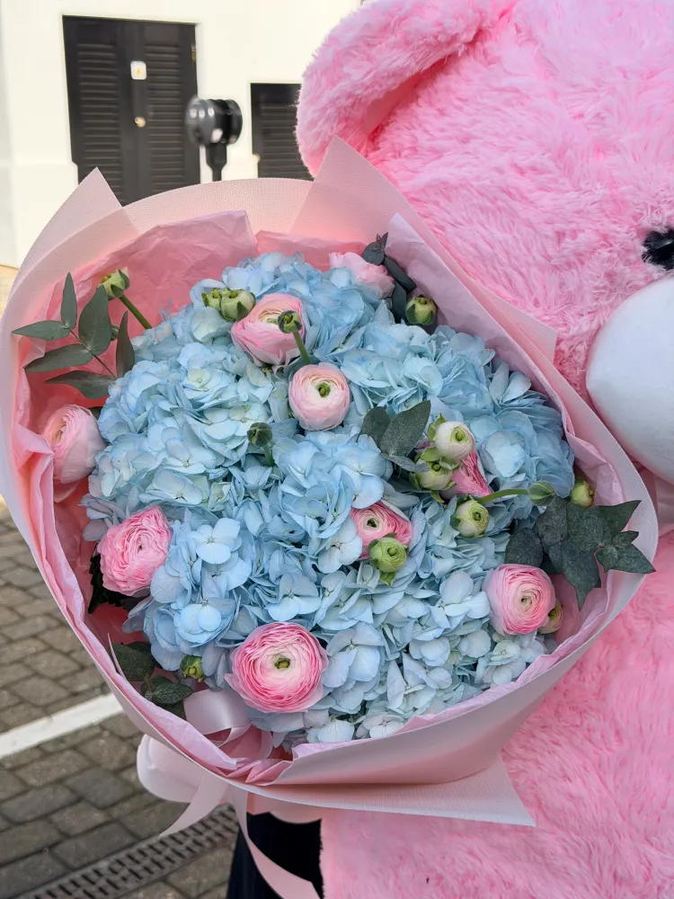 Lush light blue hydrangeas with pink ranunculi and eucalyptus, wrapped in pink tissue — Floritta