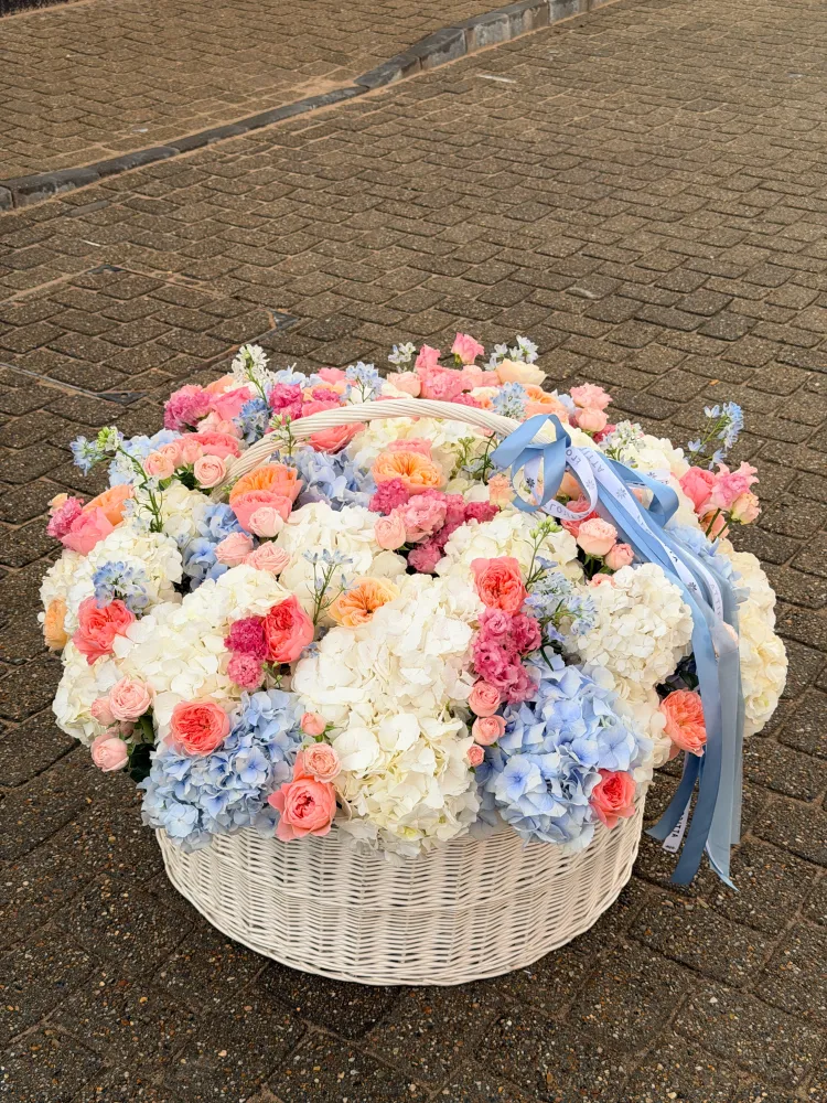 Lush hydrangea and garden rose arrangement in cream wicker basket — Floritta