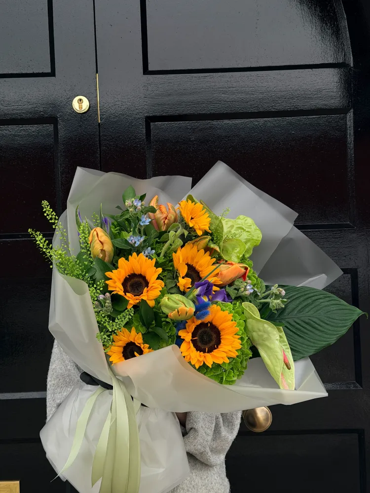 Vibrant sunflower and gerbera bouquet with delphinium, white wrap — Floritta