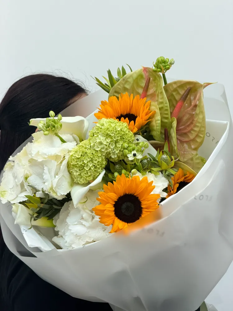 Bright gerbera and lime hydrangea arrangement with tropical foliage — Floritta