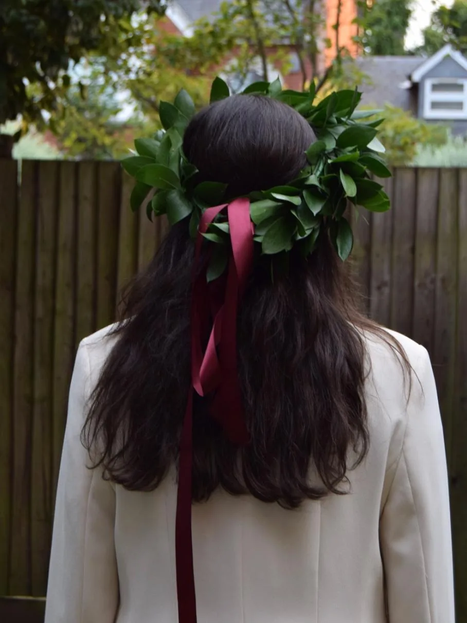 Green foliage hair wreath with burgundy ribbon