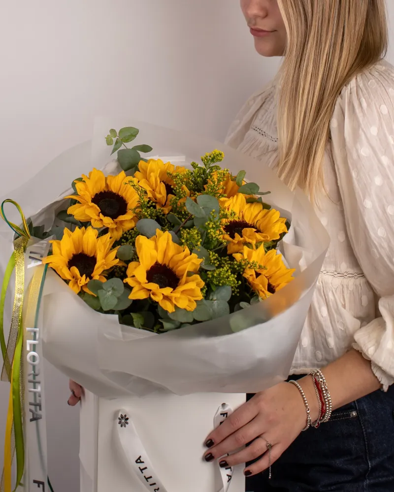 Vibrant sunflower bouquet with eucalyptus and skimmia in white wrap — Floritta